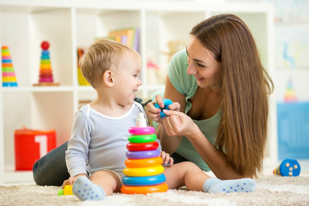 A woman and child playing with toys on the floor.