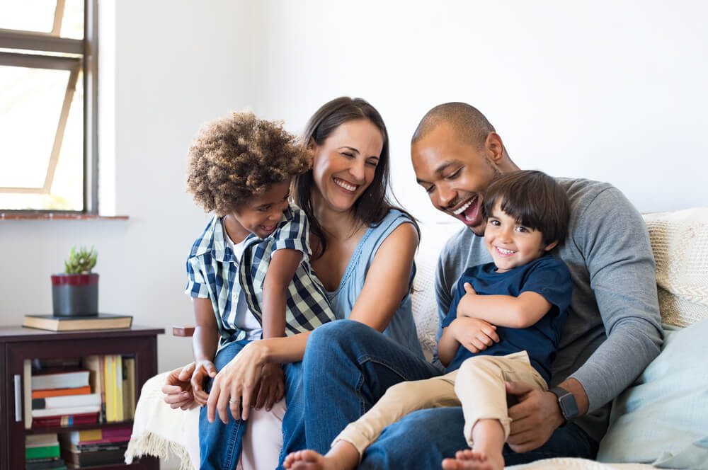 A family sitting on the couch together and smiling.