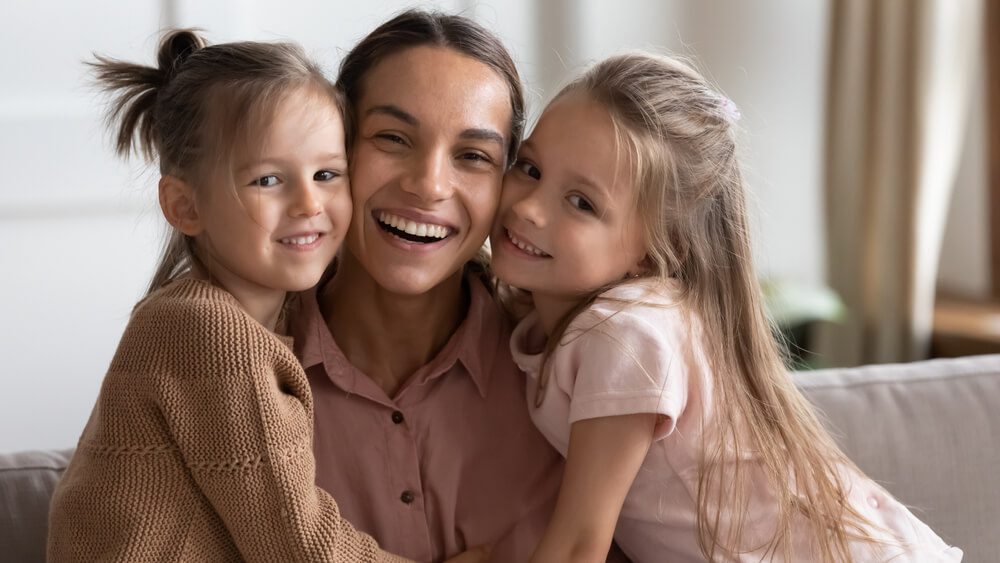 A woman and two young girls smiling for the camera.