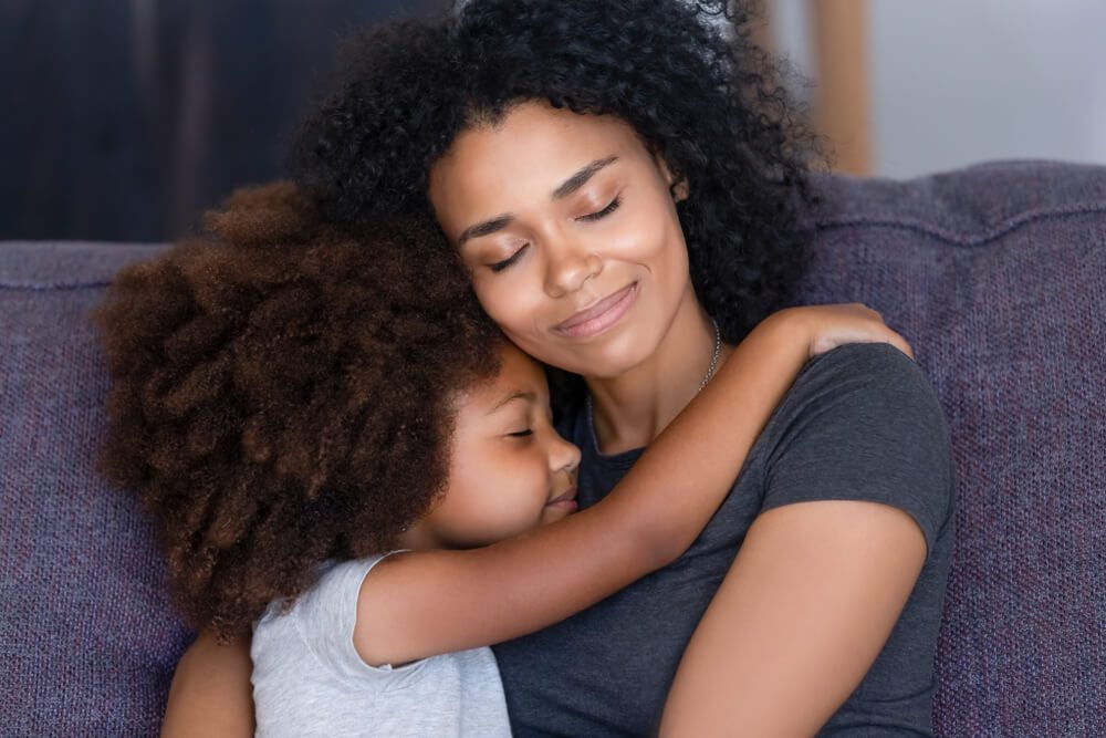 A woman and her daughter are hugging each other.