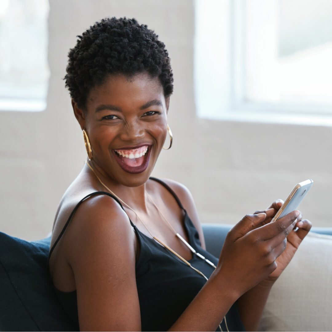 A woman smiling while holding her cell phone.